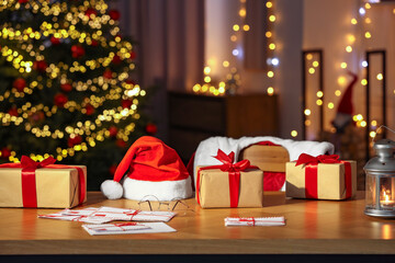 Santa's Claus workplace. Gift boxes, letters on table and costume in room with Christmas decor © New Africa