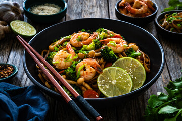 Shrimps, rice noodles, broccoli and shimeji mushrooms on wooden table 
