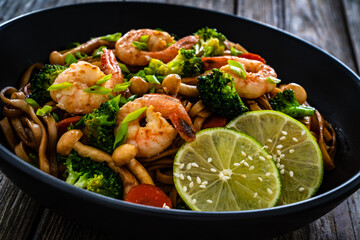 Shrimps, rice noodles, broccoli and shimeji mushrooms on wooden table 