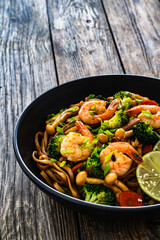 Shrimps, rice noodles, broccoli and shimeji mushrooms on wooden table 