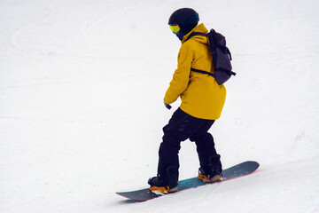 Person in a yellow jacket and black helmet riding a snowboard