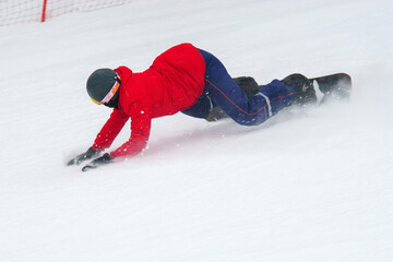 Person in a red jacket and black helmet riding a snowboard. Selective focus