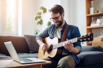 Young man playing on the guitar by the computer, online course, teatcher or student