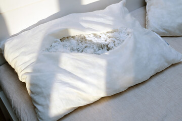 Torn old white pillow on the bed in the bedroom