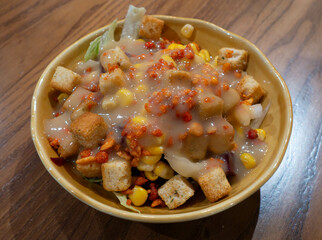 A bowl of salad at a restaurant covered in a honey mustard sauce