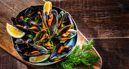 A plate of steamed mussels served with parsley and lemon