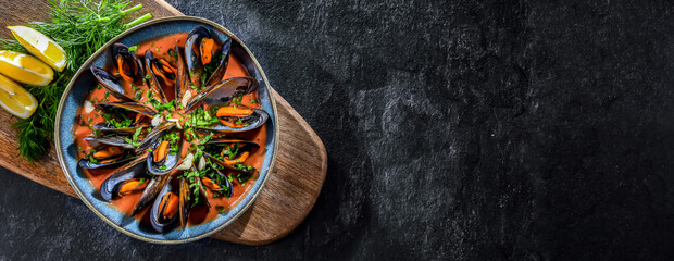 Fototapeta na wymiar A plate of mussels in tomato sauce served with parsley and lemon