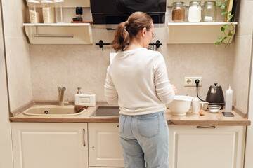 Back view of woman standing in front of sink in kitchen at home