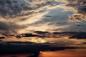 The sun shining through scattered clouds at sunset.