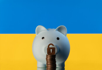 Symbolic lock and piggy bank against the background of the yellow-blue flag of Ukraine