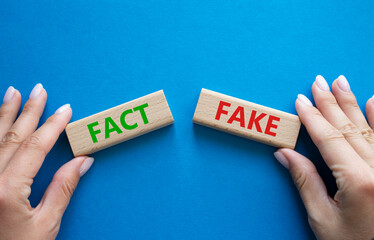 Fact or Fake symbol. Concept word Fact or Fake on wooden blocks. Businessman hand. Beautiful blue...