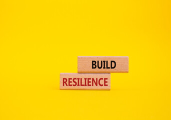 Build resilience symbol. Wooden blocks with words Build resilience. Beautiful yellow background....