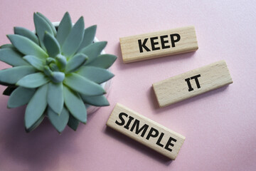 Keep it Simple symbol. Concept words Keep it Simple on wooden blocks. Beautiful pink background...