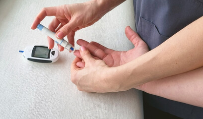 Close up shot of the glucometr instrument on the white surface. Nurse helping patient to check...