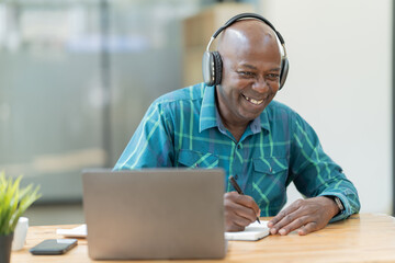Portrait of happy African American small business owner. Millennial black smiling, sitting and using the laptop, and holding a cup of coffee work in modern office.