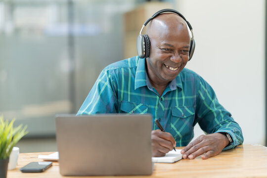 Portrait Of Happy African American Small Business Owner. Millennial Black Smiling, Sitting And Using The Laptop, And Holding A Cup Of Coffee Work In Modern Office.