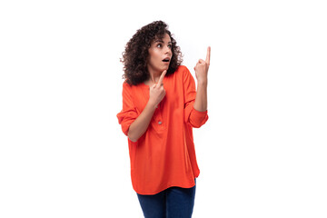 young surprised caucasian lady with curly hair style points finger towards copy space