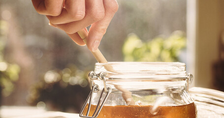 Closeup shot of organic homemade honey in a glass jar under bright sunlight