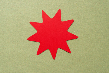 red paper nine point (or enneagram) star on rough green paper