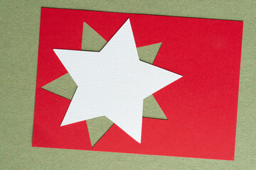 white paper star on red stencil with star shape cutout on green