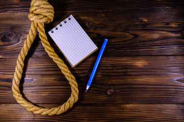 Rope with noose for the suicide, blank notepad and pen on wooden background - obrazy, fototapety, plakaty