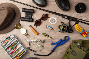 Fishing rod, tackles and other stuff for recreation activity on the wooden desk. Fishing season concept - obrazy, fototapety, plakaty
