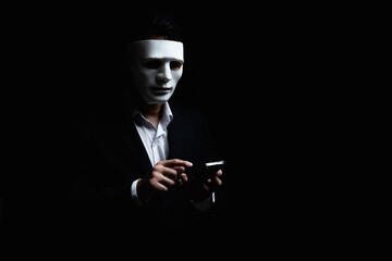 Unknown businessman wearing mask with covered face using mobile phone makes an anonymous call...