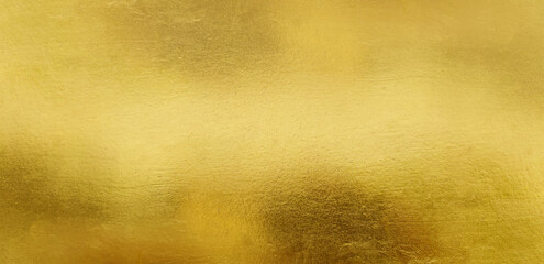 Gold wall texture background. Yellow shiny gold foil paint on wall surface with light reflection, vibrant golden luxury wallpaper, horizontal