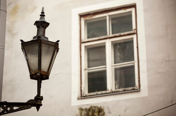 Fototapeta na wymiar Vintage street lamp on the wall of a house with a window in the city. Photo