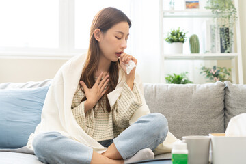 Sick, coronavirus or covid-19, illness asian young woman, girl with blanket have a fever, flu or sore throat and sneezing until chest pain while rest at home. Health care with disease, pandemic virus.