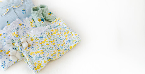 Clothing for babies and knitted socks on a white background with copy space. Children's fashion made from organic cotton, recycled textiles. Banner