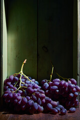 Bunch of ripe organic grown grapes in a wooden box in bright sunlight with copyspace. Natural fruit from garden concept image.