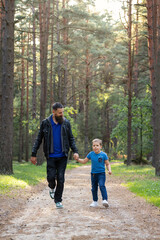 Bearded father and son walking hand in hand on a forest footpath