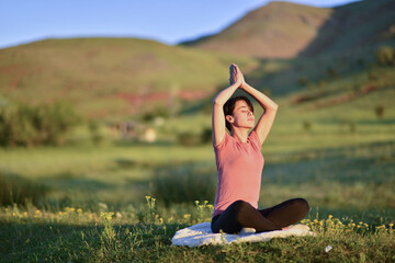 young woman doing yoga at the foot of the mountain