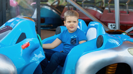Little boy having fun riding big blue bumper car