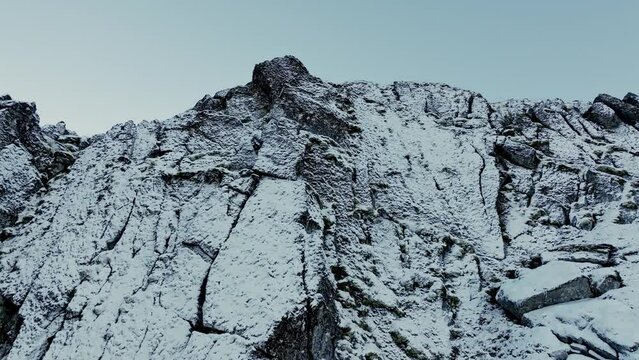 Winter magic at Mount Norway Lofoten, where the mountain peak wears a snowy blanket under the cold winter sun and blue skies.