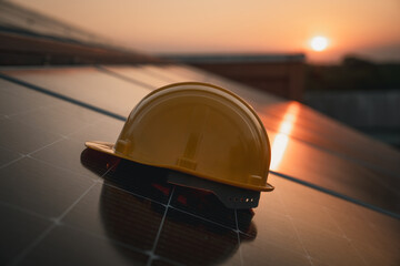 Yellow engineer hard safety helmet hat on solar cell panel. Clean energy concept.