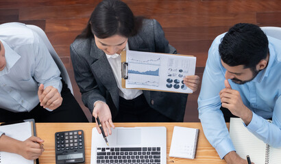Top view multiracial analyst team use BI dashboard data to analyze financial report on meeting table. Group of diverse business people utilize data analysis by FIntech for business decision. Concord
