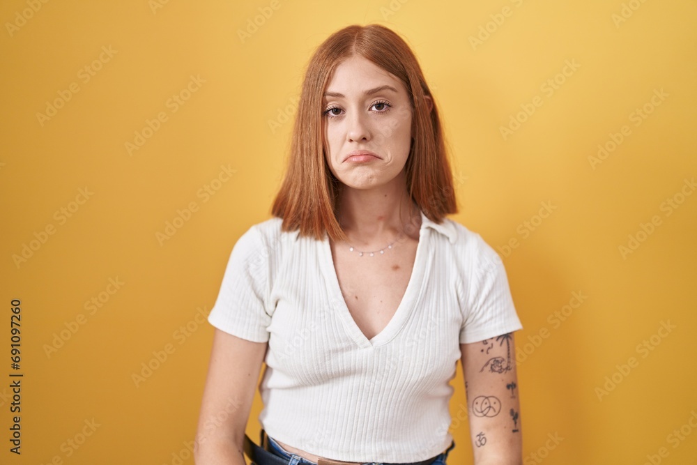 Poster young redhead woman standing over yellow background depressed and worry for distress, crying angry a