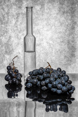 Still life with a bottle of liquid and bunches of grapes