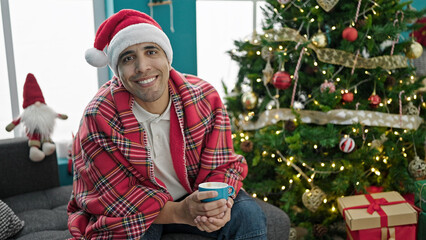 Young hispanic man drinking coffee celebrating christmas at home