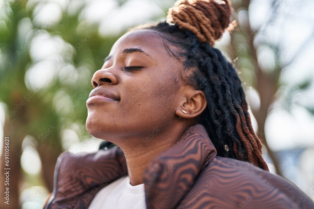 Wall mural African american woman breathing with closed eyes at park