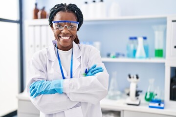 African american woman scientist smiling confident standing with arms crossed gesture at laboratory