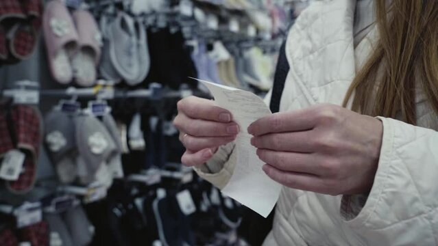 a girl with a receipt and a smartphone in the supermarket