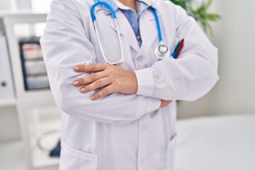 Young beautiful hispanic woman doctor standing with arms crossed gesture at clinic