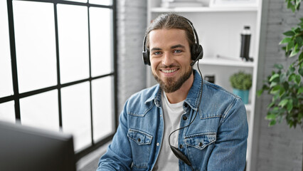 Young hispanic man business worker using computer and headphones smiling at the office