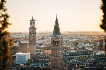 Two striking old church towers looking over the inner city in Italy at sunset as seen from afar