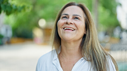Middle age hispanic woman smiling confident looking to the sky at park