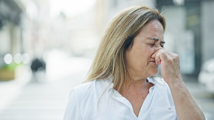 Middle age hispanic woman sneezing at street - obrazy, fototapety, plakaty