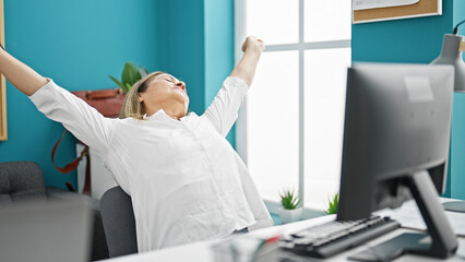 Middle age hispanic woman business worker using computer tired stretching arms at the office